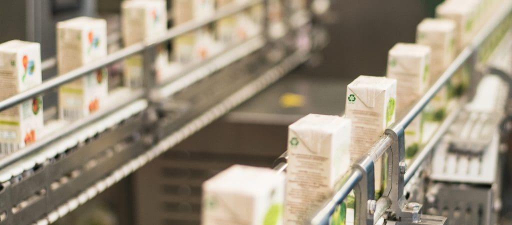 A production line full of juice boxes that have been printed upon by coding and marking machinery