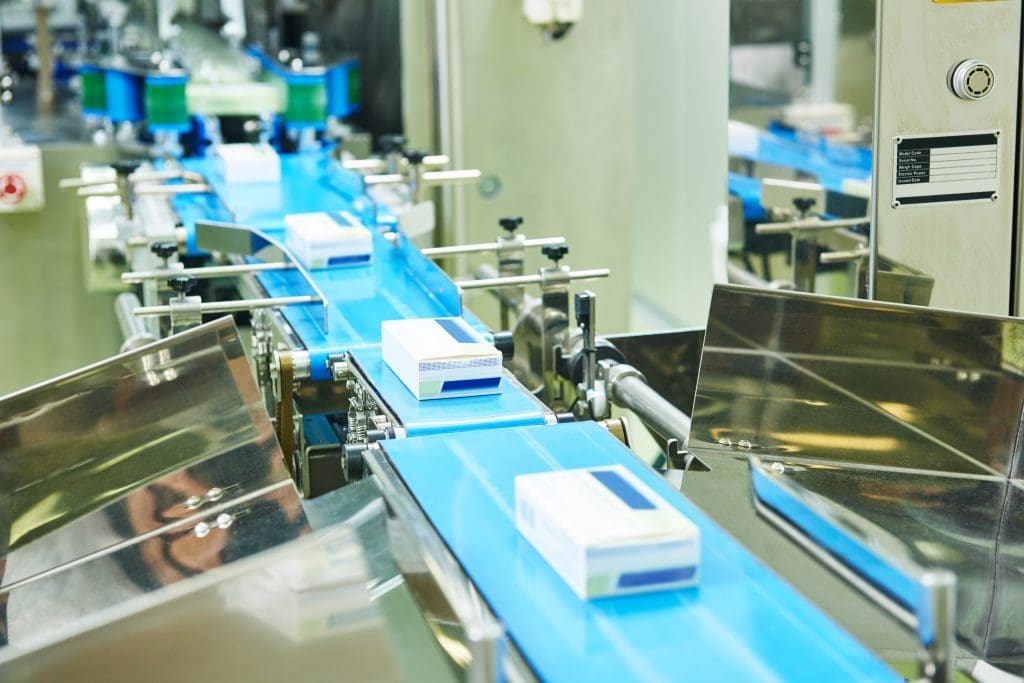 A series of conveyors with pharmaceutical boxes moving along them.