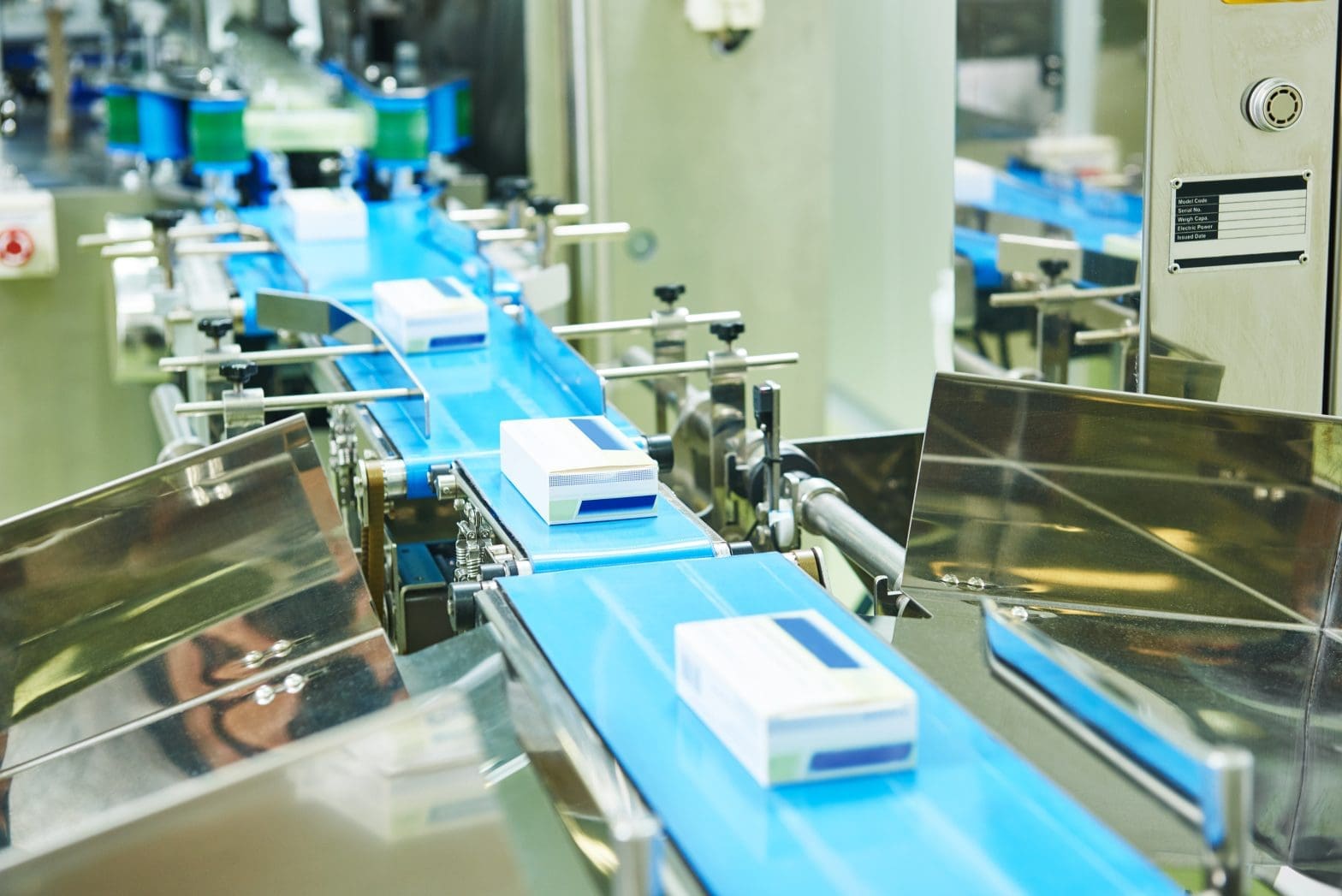 A series of conveyors with pharmaceutical boxes moving along them.