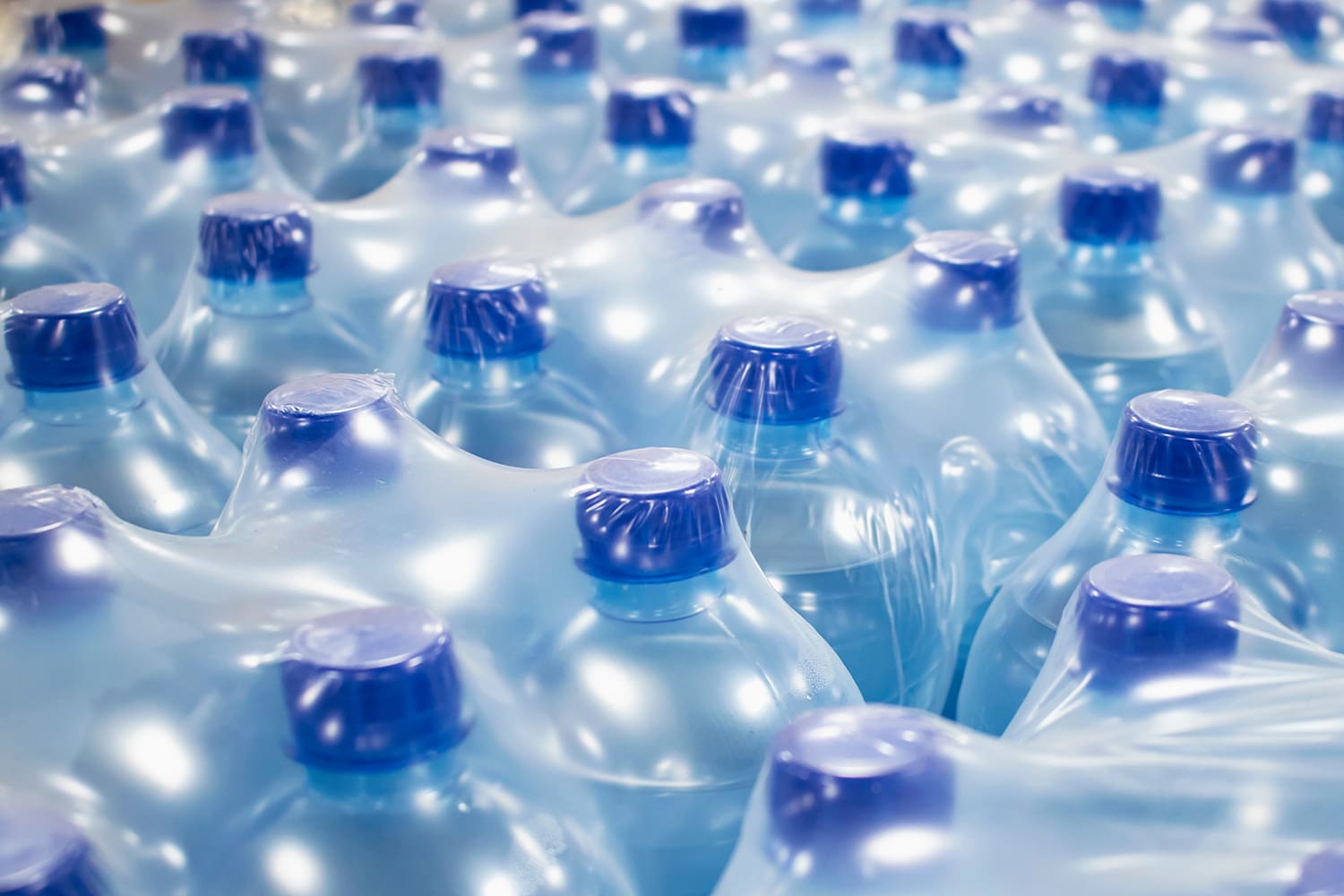 A close-up of plastic water bottles within shrink-wrapped cases