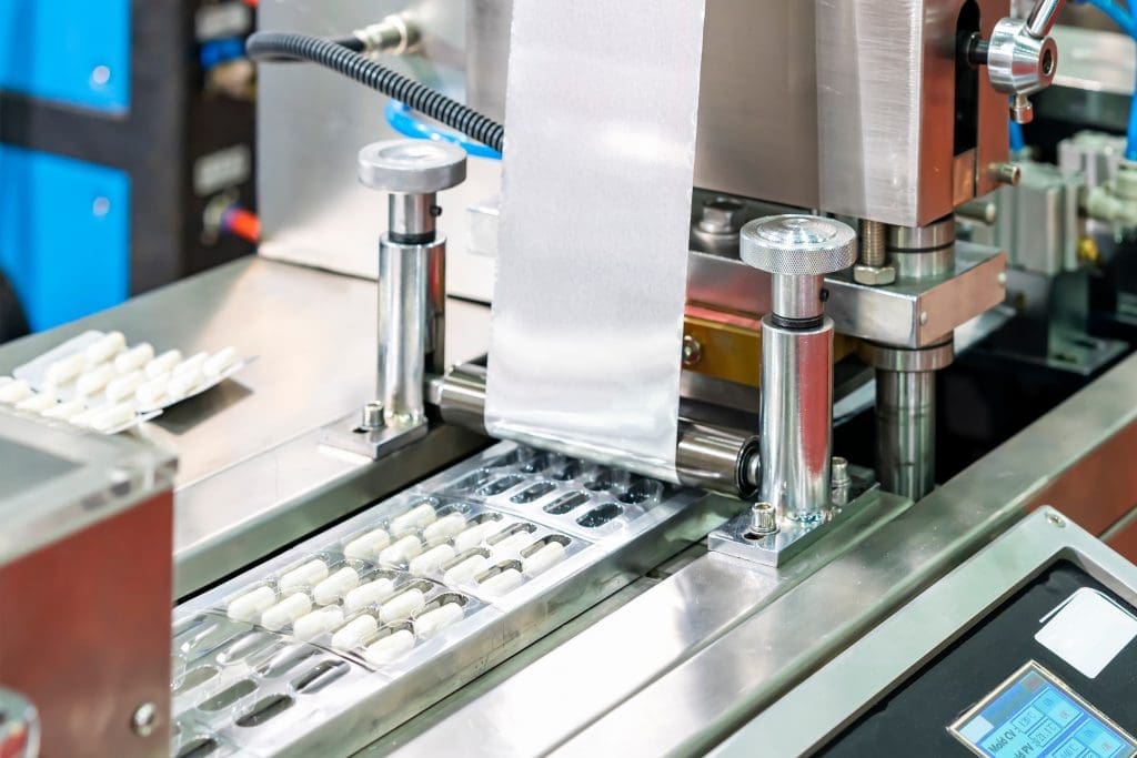 Supplement pill packaging moving through a machine to be sealed.