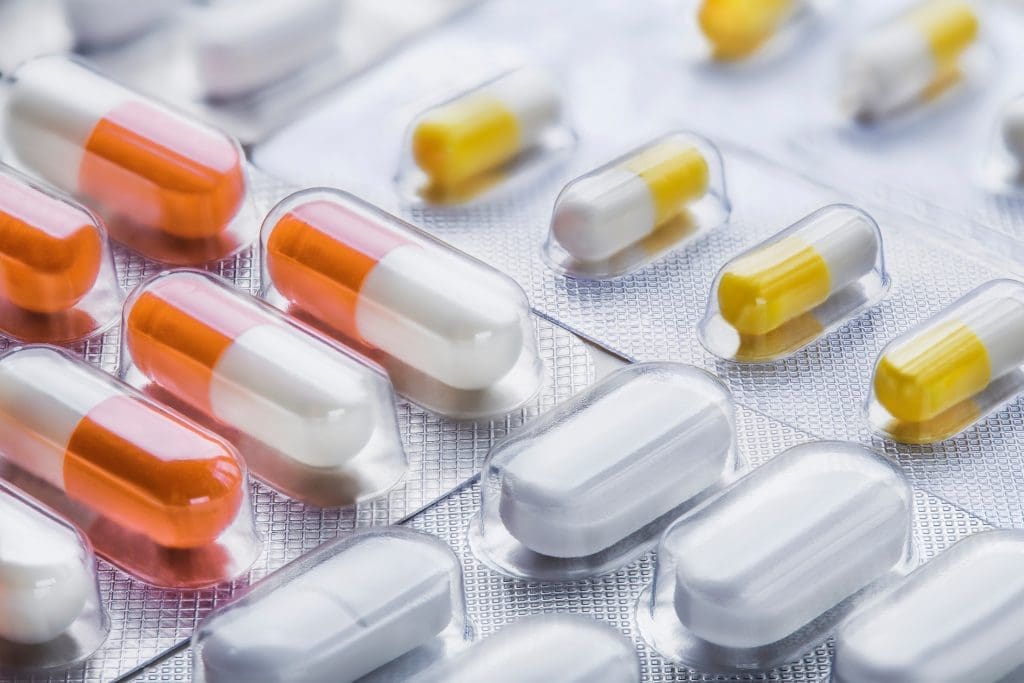 A closeup of bubble pill packaging with foil backing and different colored pills.